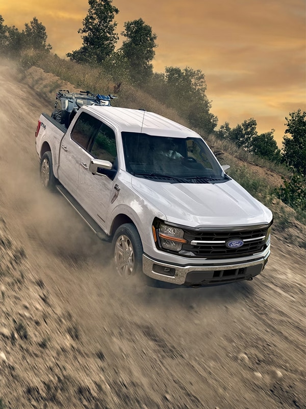 A white 2026 F-150® truck being driven down a steep, rocky incline