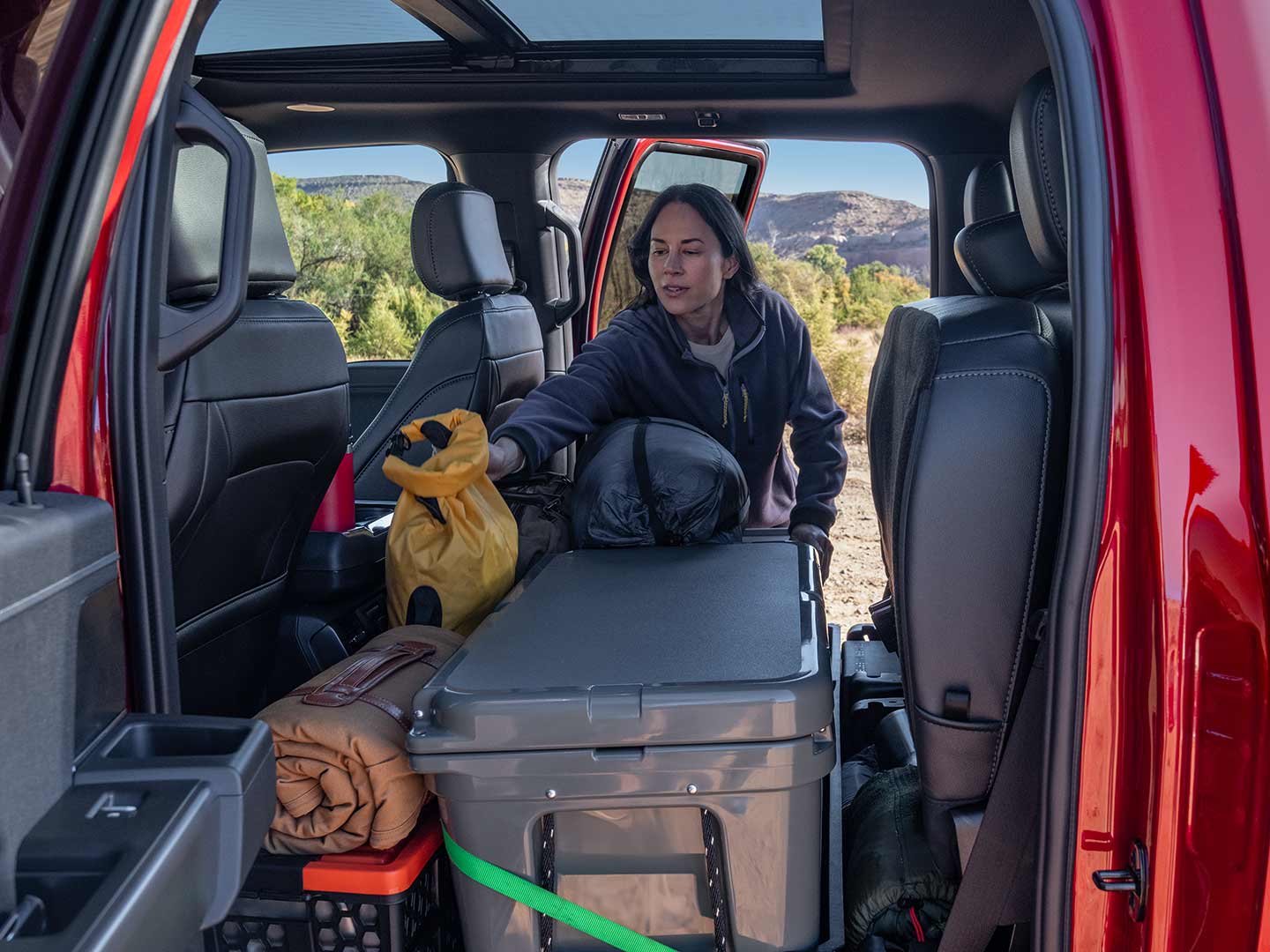 Woman loading items into the rear seating area of a 2024 F-150<sup>®</sup> truck with the seats folded up