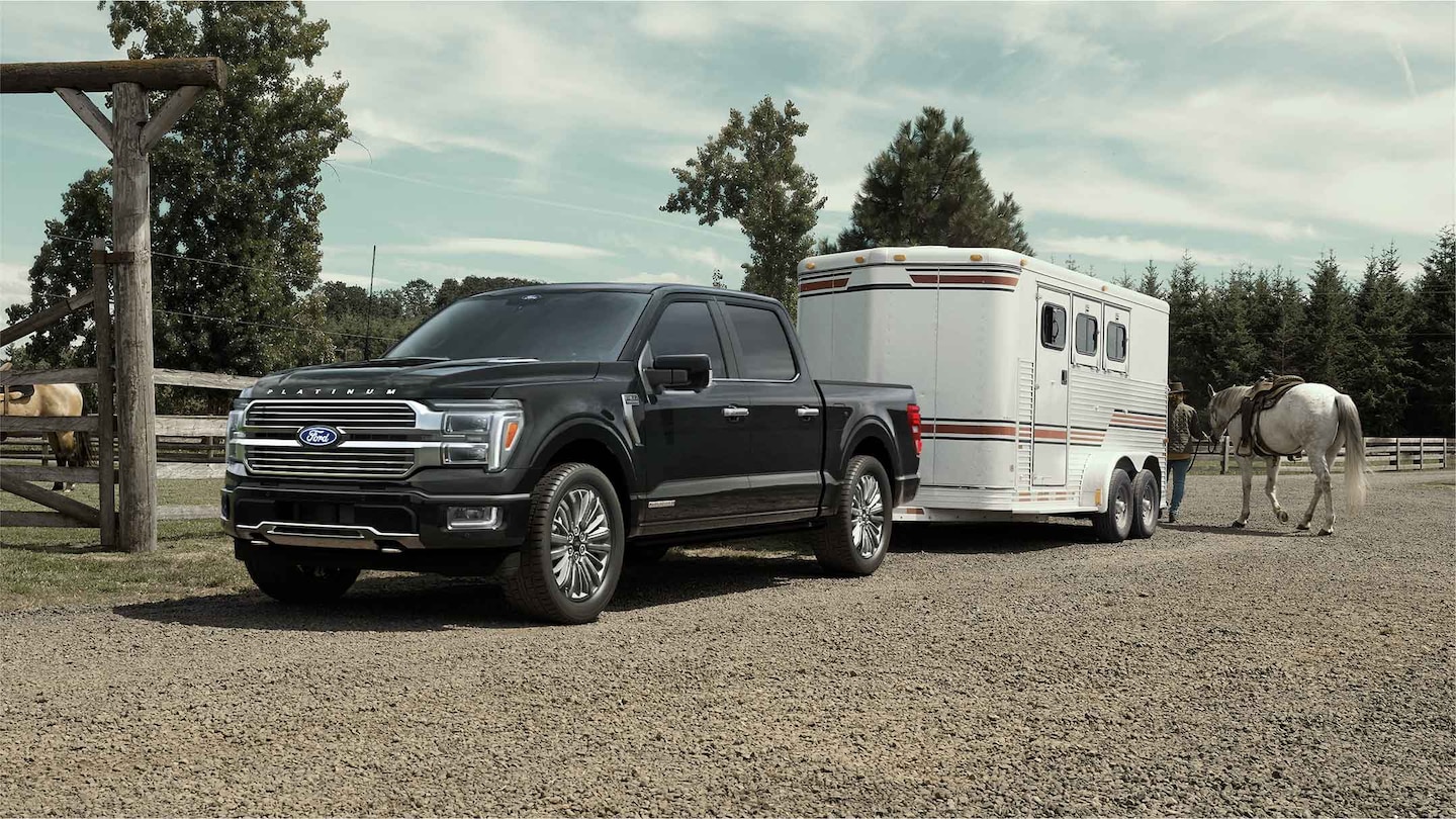  2025 Super Duty® hitched to a horse trailer with a horse and person at the back.