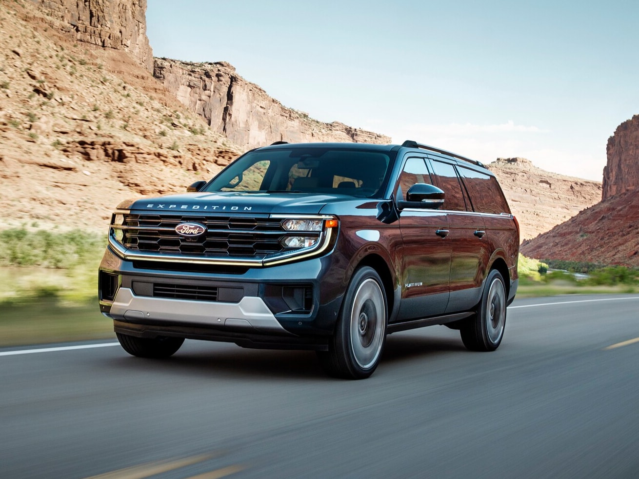  2025 Ford Expedition® Platinum MAX model driving down a mountain-lined road.