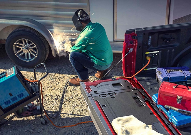 Person using a TIG welder that's plugged into the Pro Power Onboard feature located in the truck bed