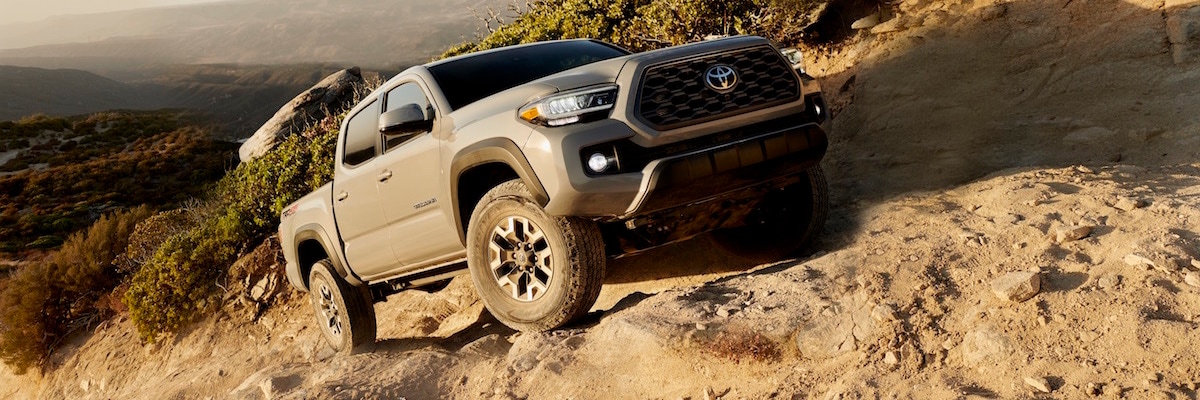 A silver 2019 Toyota Tacoma TRD Off-Road driving up a rocky hill