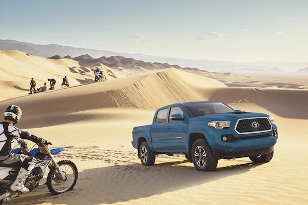 A blue 2019 Toyota Tacoma parked in sand dunes