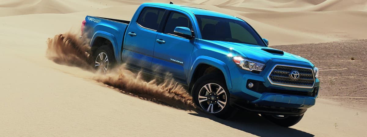 A blue 2019 Toyota Tacoma TRD Sport driving through the sand