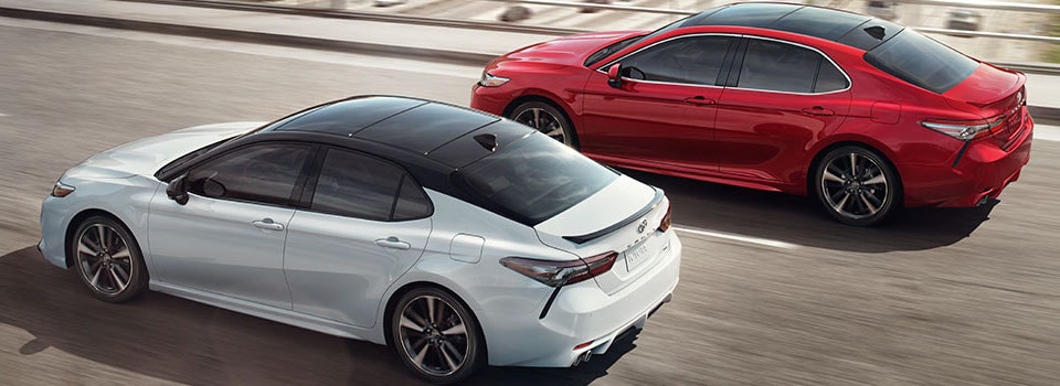 2019 Toyota Camry A white & red Toyota Camry driving down a road