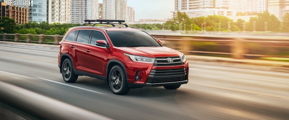 A red 2019 Toyota Highlander driving down an open road