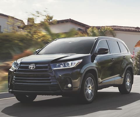 A black 2019 Toyota Highlander driving through a suburb