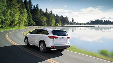2019 Toyota Highlander A white 2019 Toyota Highlander driving around a lake