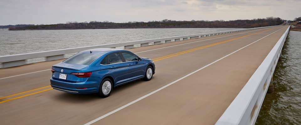 A blue 2019 VW Jetta driving down a bridge