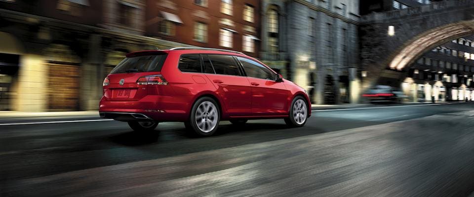 A tornado red Volkswagen Gold Sportwagen driving through a city street