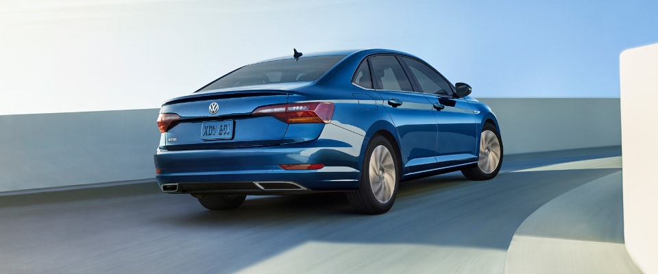 A blue 2019 Volkswagen Jetta driving on a curved highway