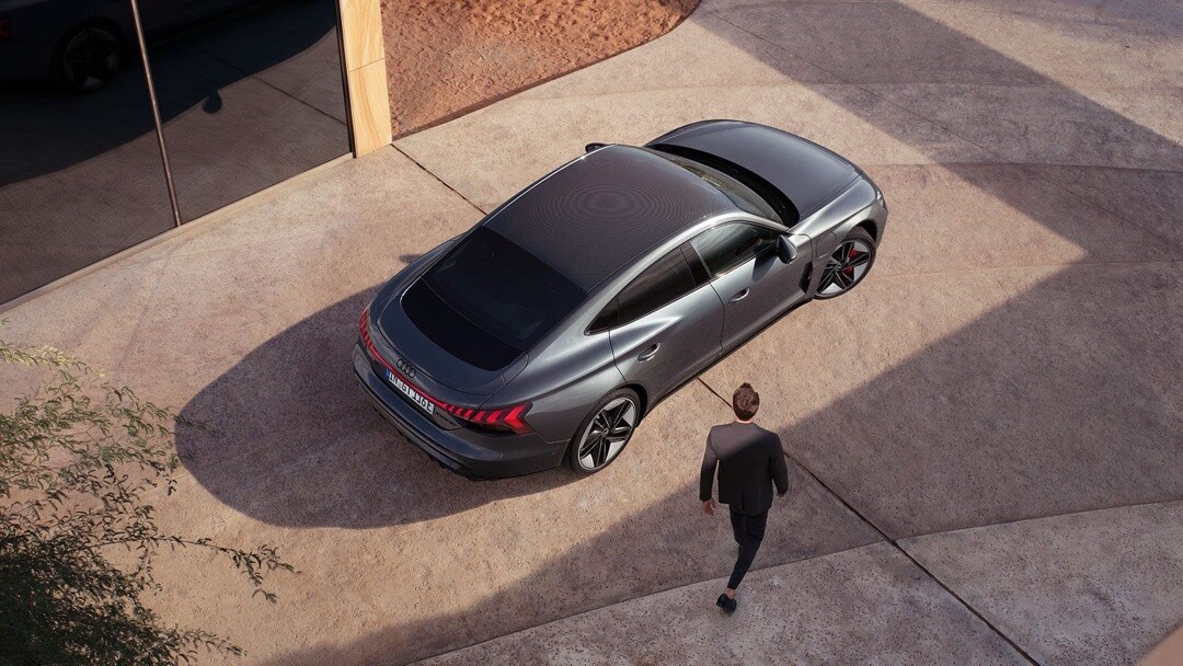 Un homme marche vers la Audi RS e-tron GT 2023 grise.	