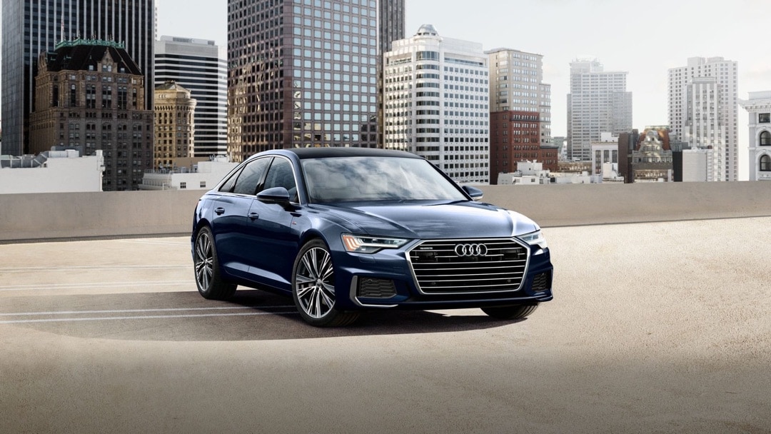 Vue 3/4 avant de la Audi A6 2023 garé devant un horizon urbain.