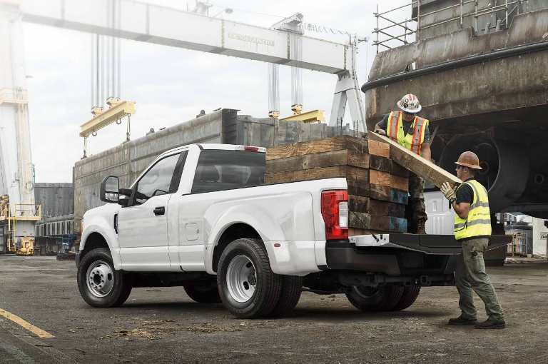 New White Ford Super Duty Pickup Truck with a Full Payload of Logs at a Construction Site