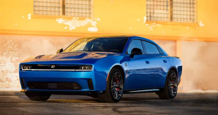 Blue 2026 Dodge Charger parked in front of an industrial building.