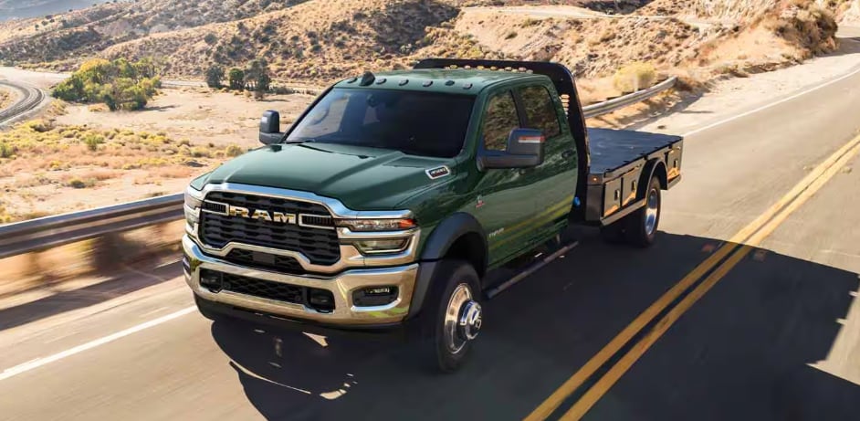 2026 RAM 3500 Chassis Cab driving on a highway with flatbed upfit