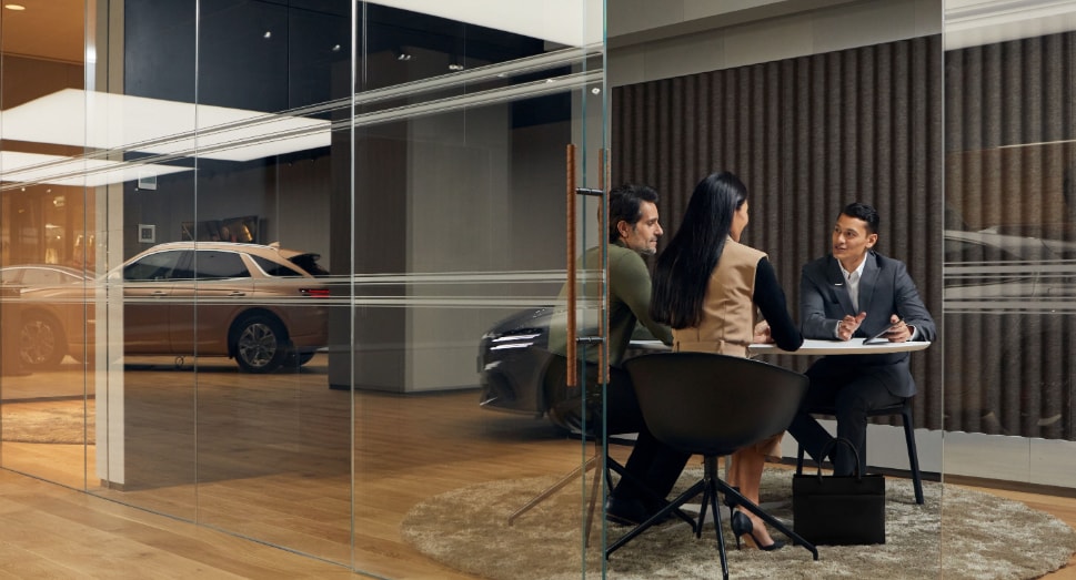 Genesis sales representative talking to couple at desk.