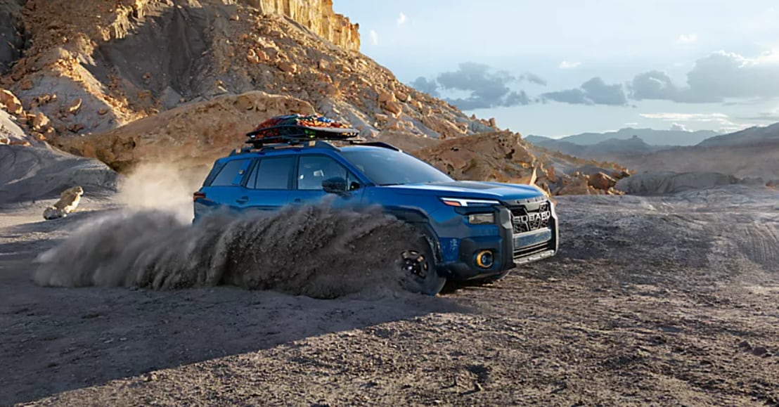 Blue 2026 Subaru Outback in sandy terrain.