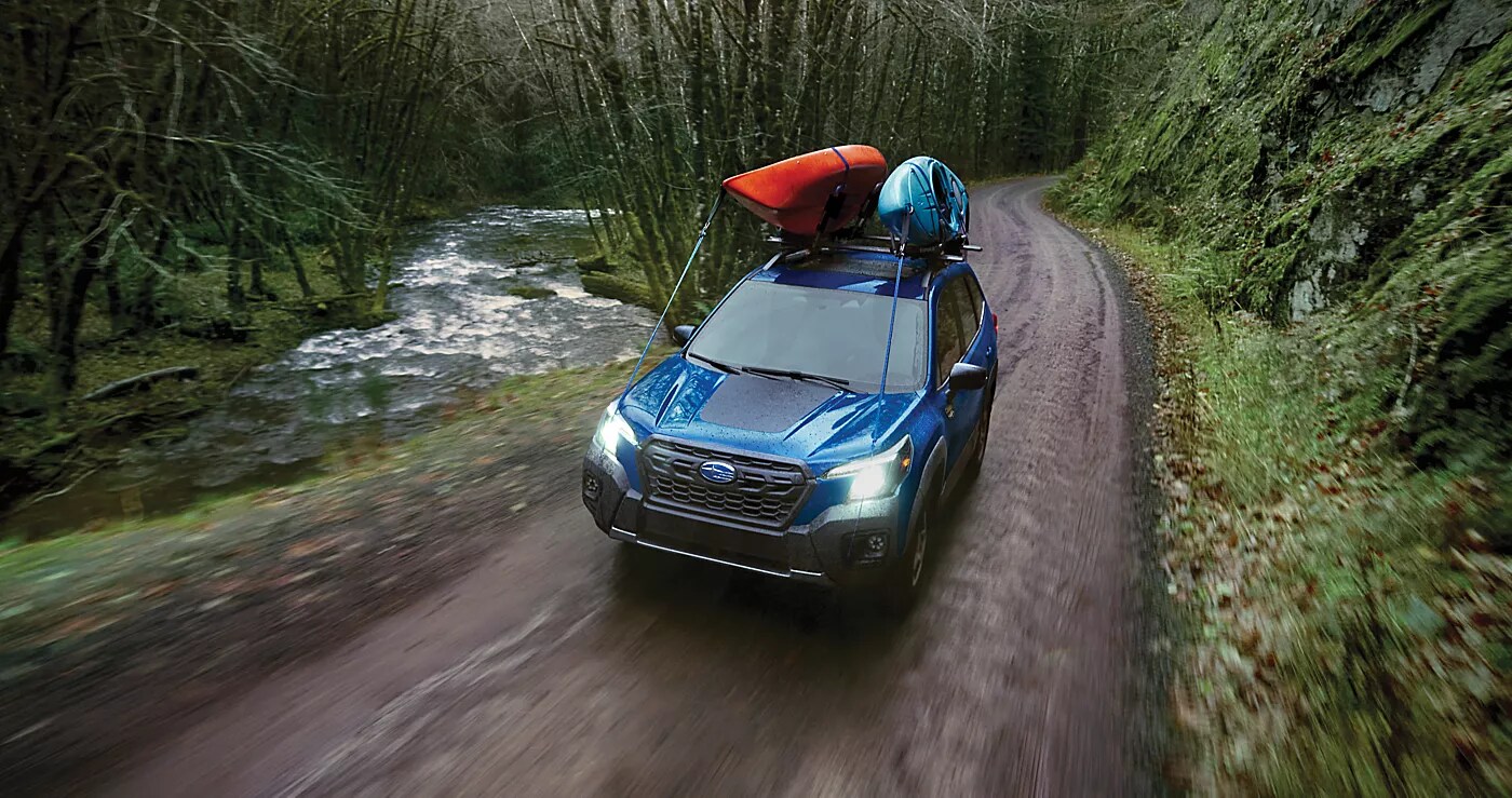 A Subaru Certified Pre-Owned SUV driving through a forest