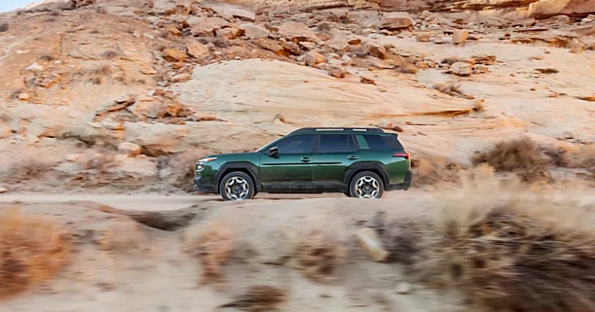 Green 2026 Subaru Outback driving fast on highway.