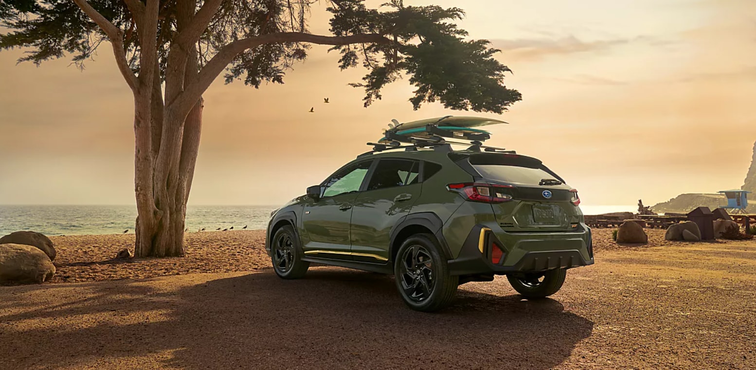 Green 2027 Subaru Crosstrek parked at the beach at dusk