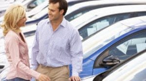 A customer talking with a salesperson in a car lot.