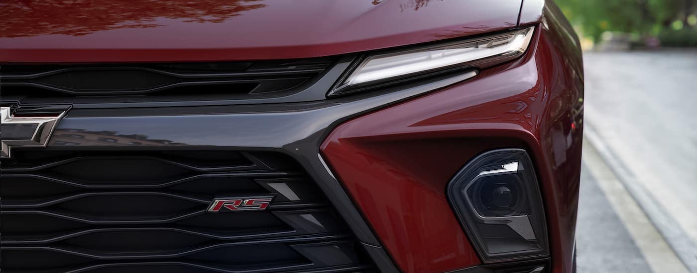 A close up shows the driver side headlight on a red 2023 Chevy Blazer RS.