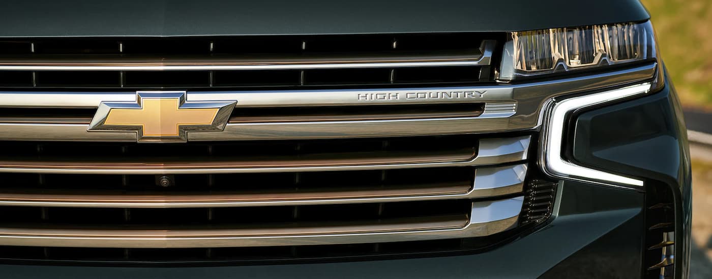 A close up shows the grille and driver side headlight on a dark grey 2022 Chevy Tahoe High Country.