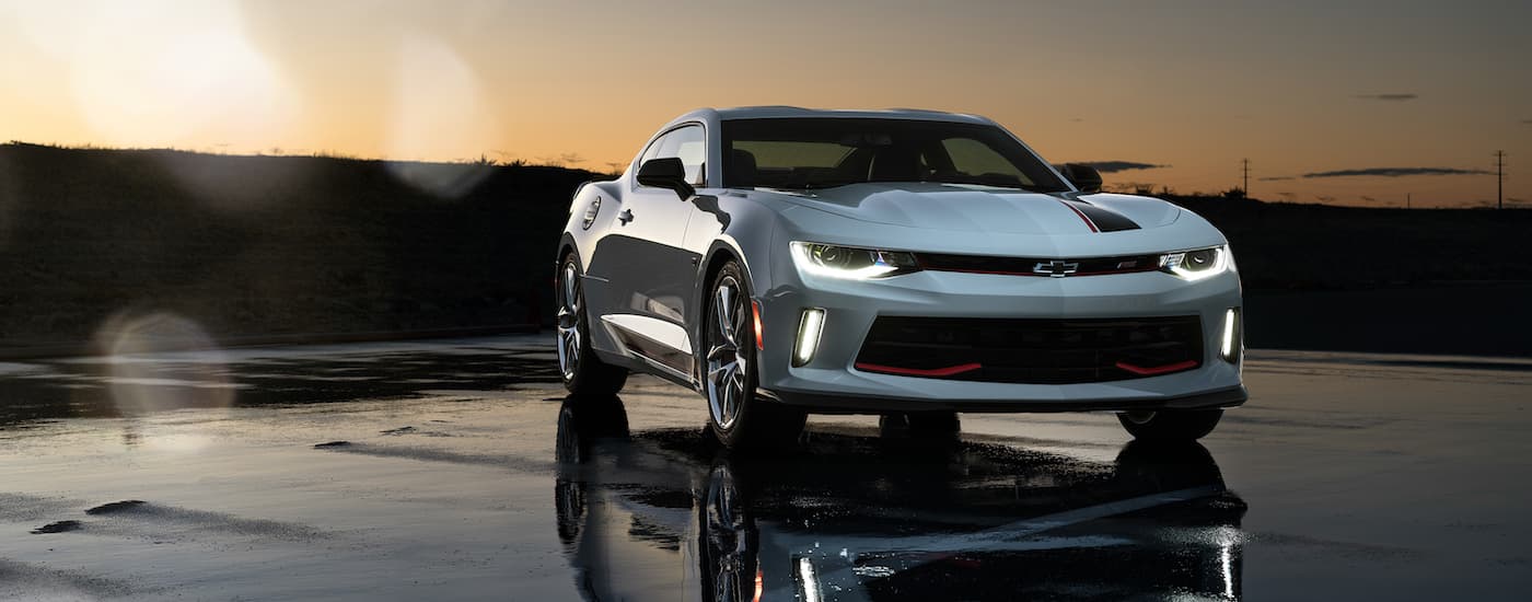 A white 2016 Chevy Camaro RS parked on wet pavement showing its reflection.