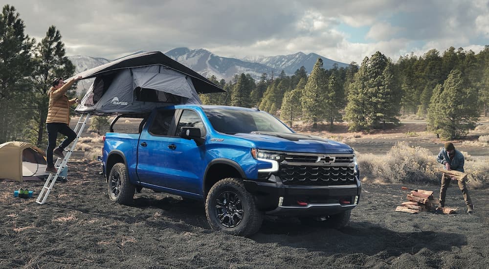 A blue 2023 Chevy Silverado ZR2 is shown at a remote campsite.