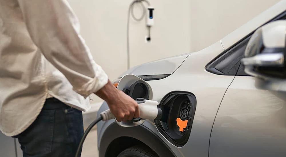 Plugging in a silver 2022 Chevy Bolt EV to charge in a residential garage