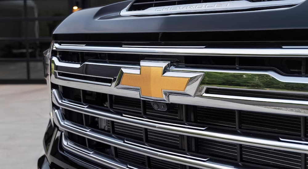 A close up of the grille on a black 2024 Chevy Silverado 2500 HD with forward cameras
