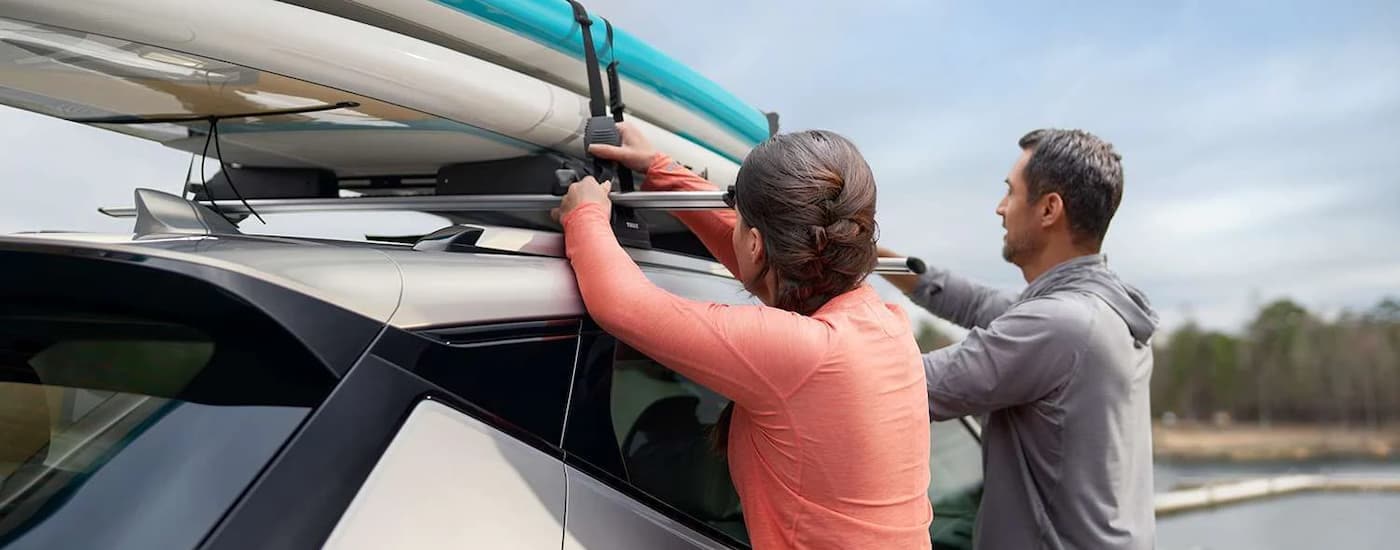 A silver 2023 Chevy Bolt EUV is shown with surfboards on the roof.