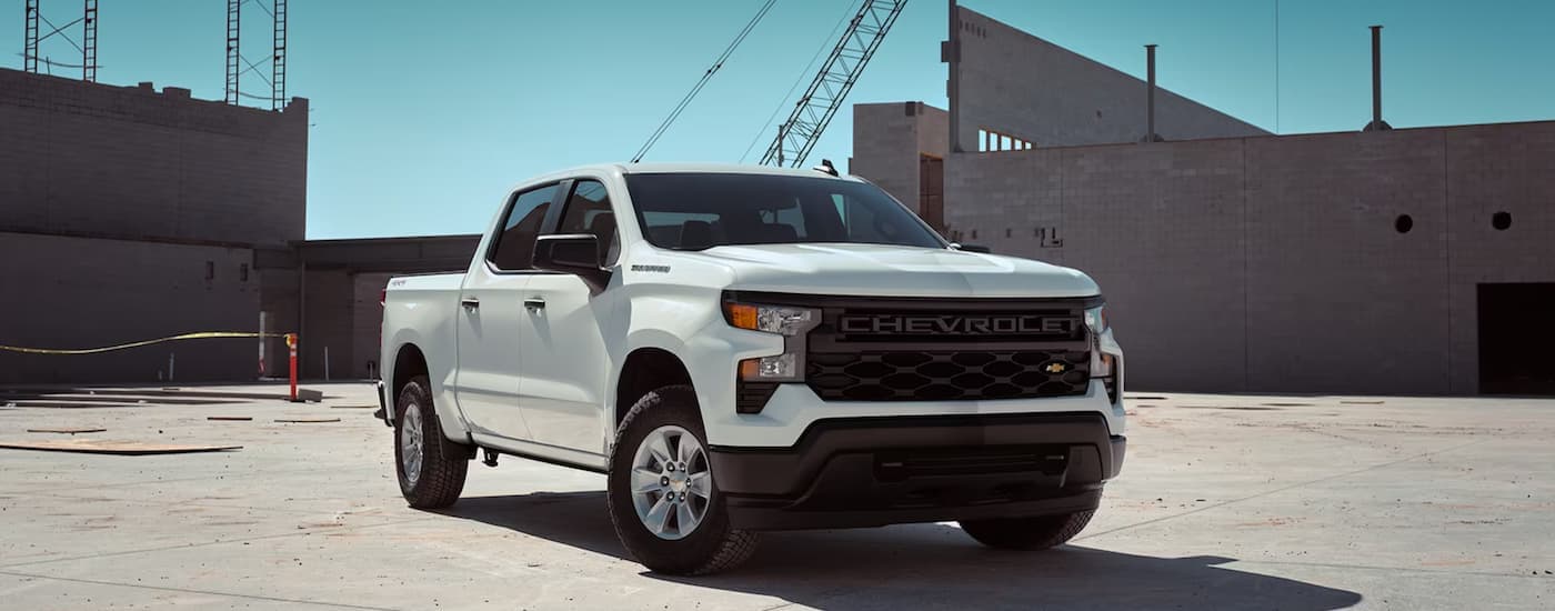 A white 2023 Chevy Silverado 1500 WT is shown parked at a construction site.