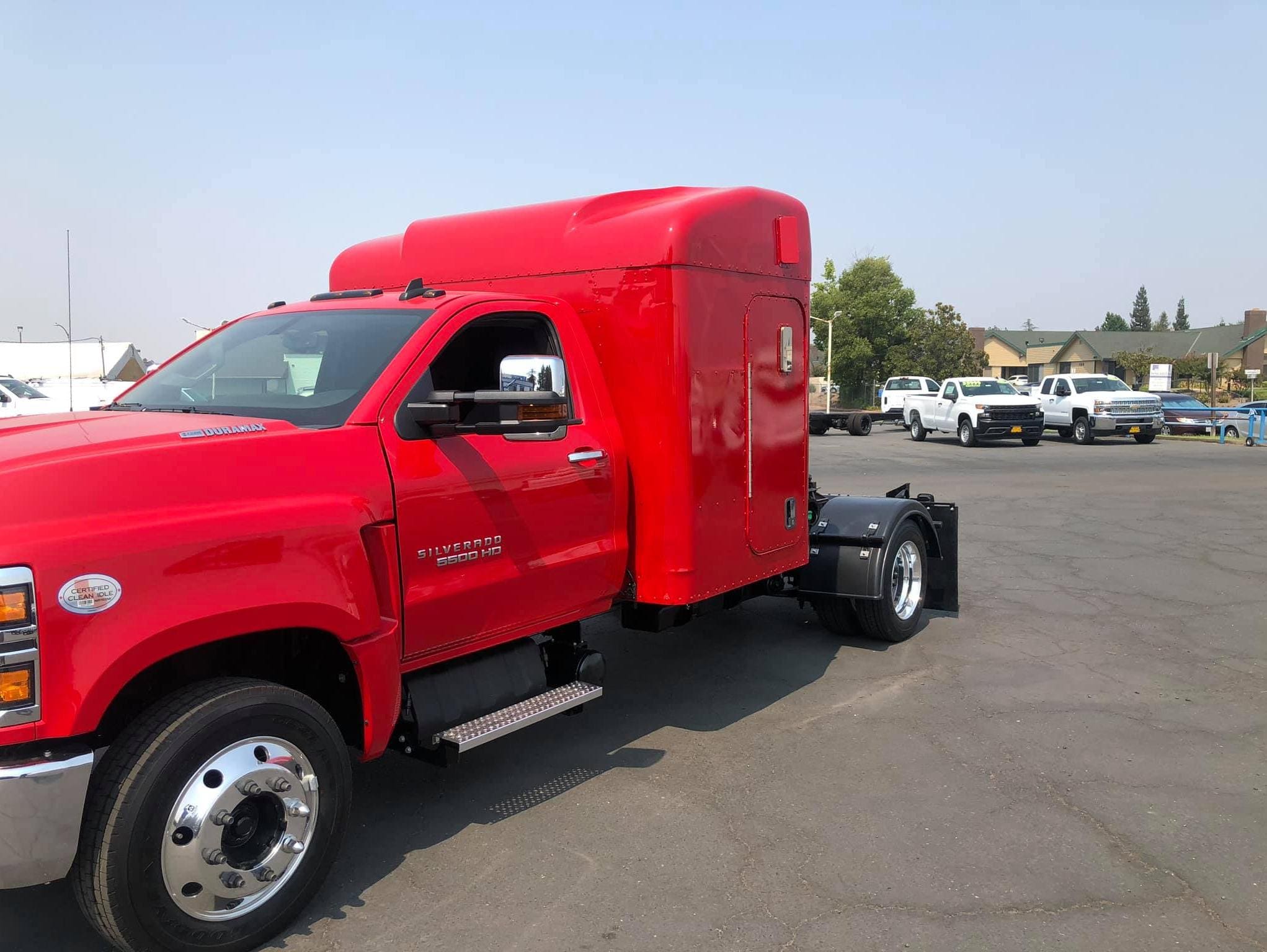 Front view of a red Chevy Silverado 5500HD with camper and hauler body