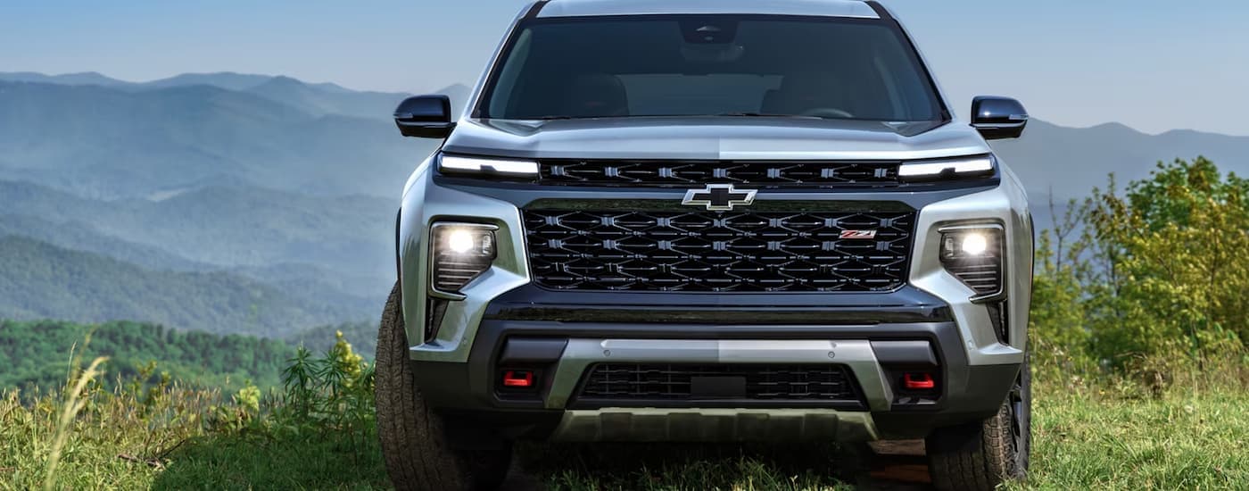 A grey 2024 Chevy Traverse Z71 is shown from the front parked in grass overlooking a mountain view.
