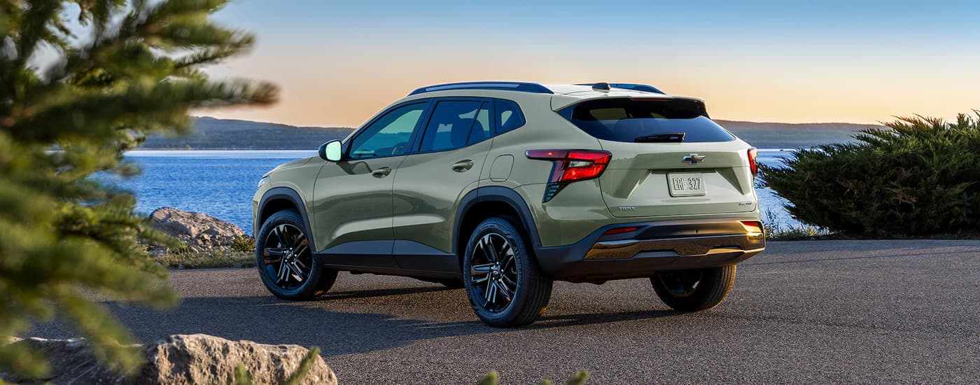 A green 2024 Chevy Trax Activ is shown from the rear parked near a lake.