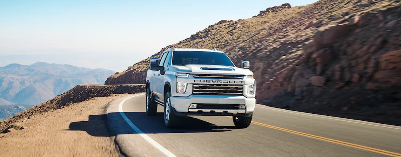 A white 2023 Chevy Silverado 3500HD Z71 is shown driving on an open highway.