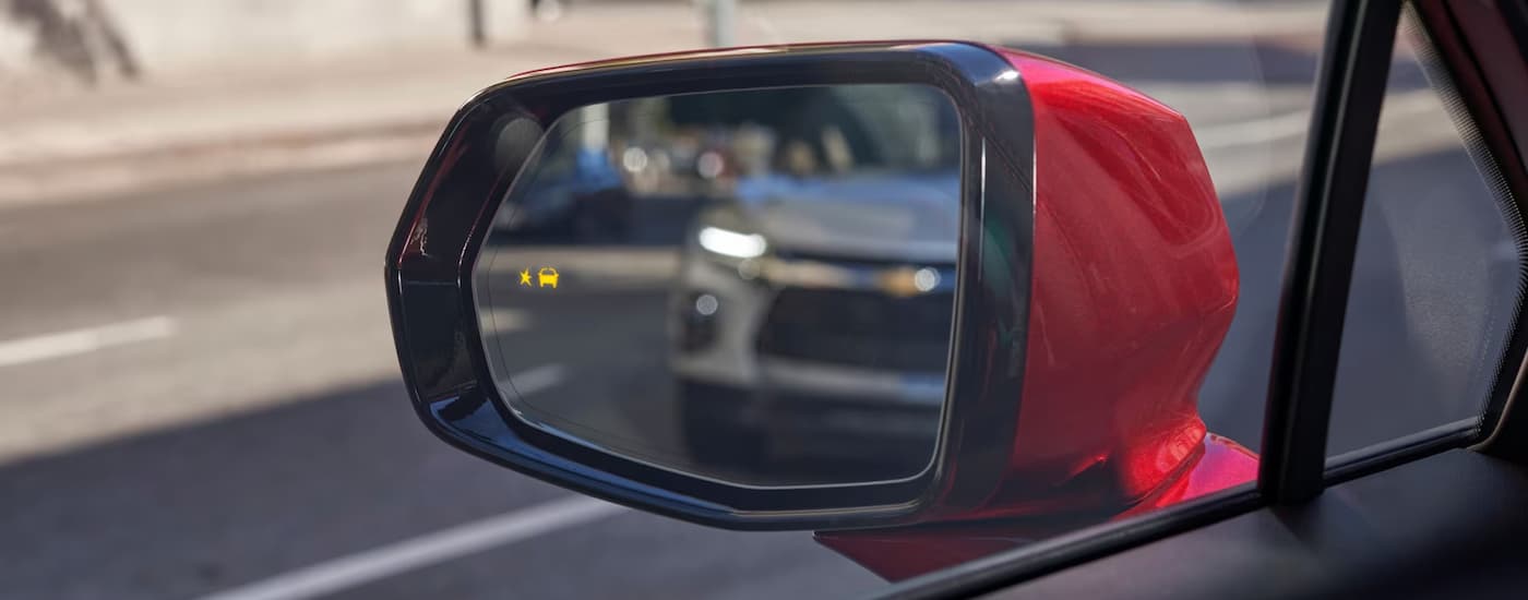 Chevy Blazer for sale - 2023 Chevy Blazer - Rear View Mirror.jpg The side mirror of a red 2023 Chevy blazer with the Side Blind Zone Alert symbol illuminated.