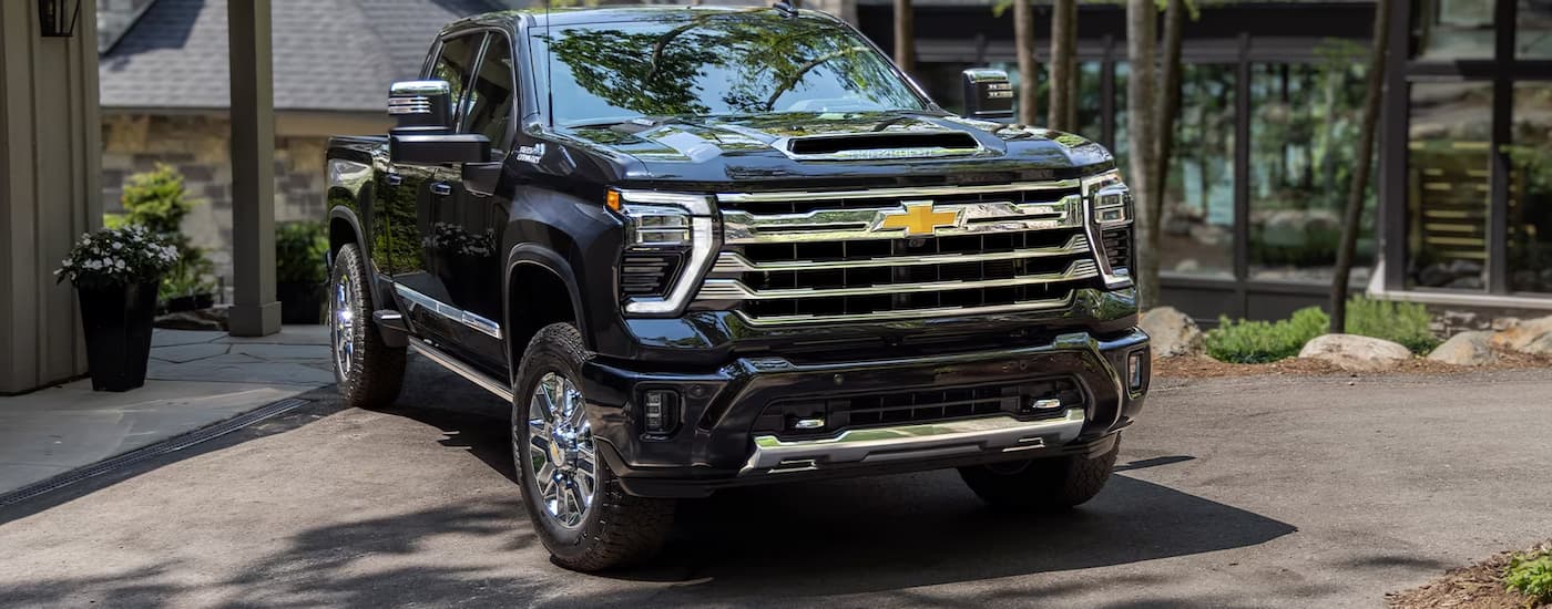 A black 2024 Chevy Silverado 2500HD High Country parked in front of a modern home.