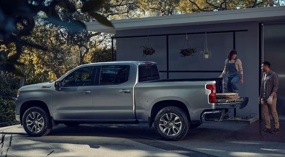 A man and woman loading building materials into the back of a silver 2024 Chevy Silverado 1500 Z71.