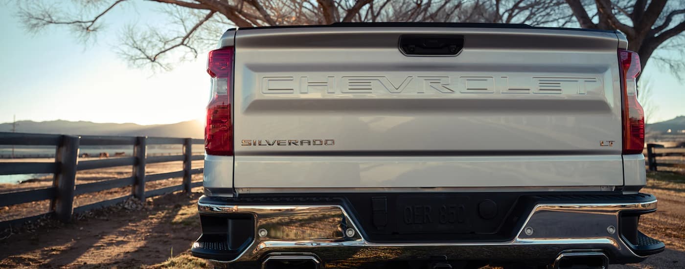 A close up of the tailgate of a silver 2023 Chevy Silverado 1500 LT parked on a farm.