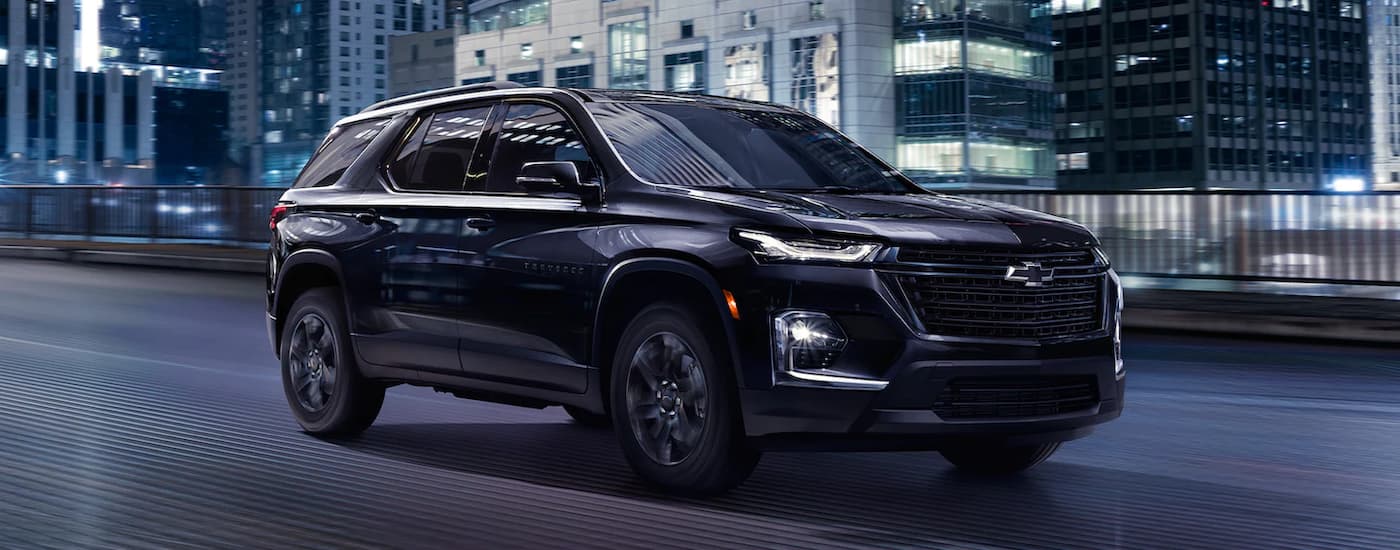 A black 2022 Chevy Traverse Midnight Edition is shown driving on a city street.