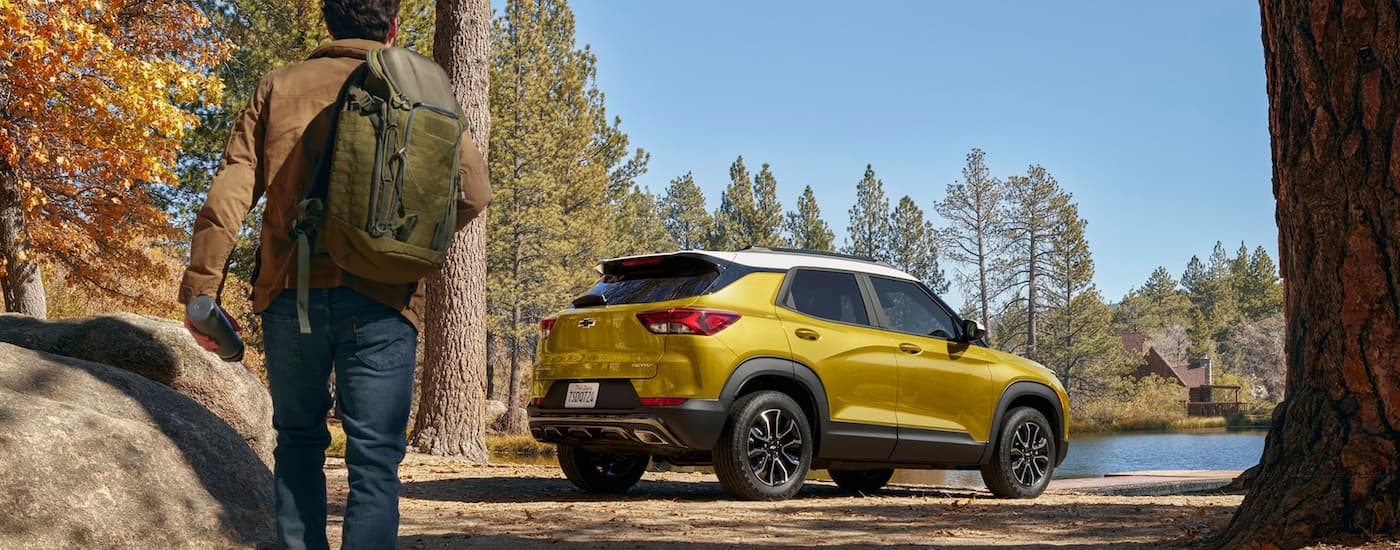 A yellow 2023 Chevy Trailblazer Activ is shown from a rear angle parked at a hiking trail.