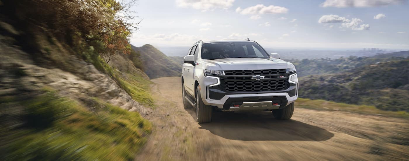 A white 2022 Chevy Tahoe Z71 is shown driving down a mountain trail.