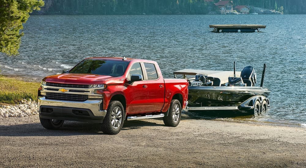 A red  2022 Chevy Silverado 1500 Z71 is shown backing a boat into a lake.