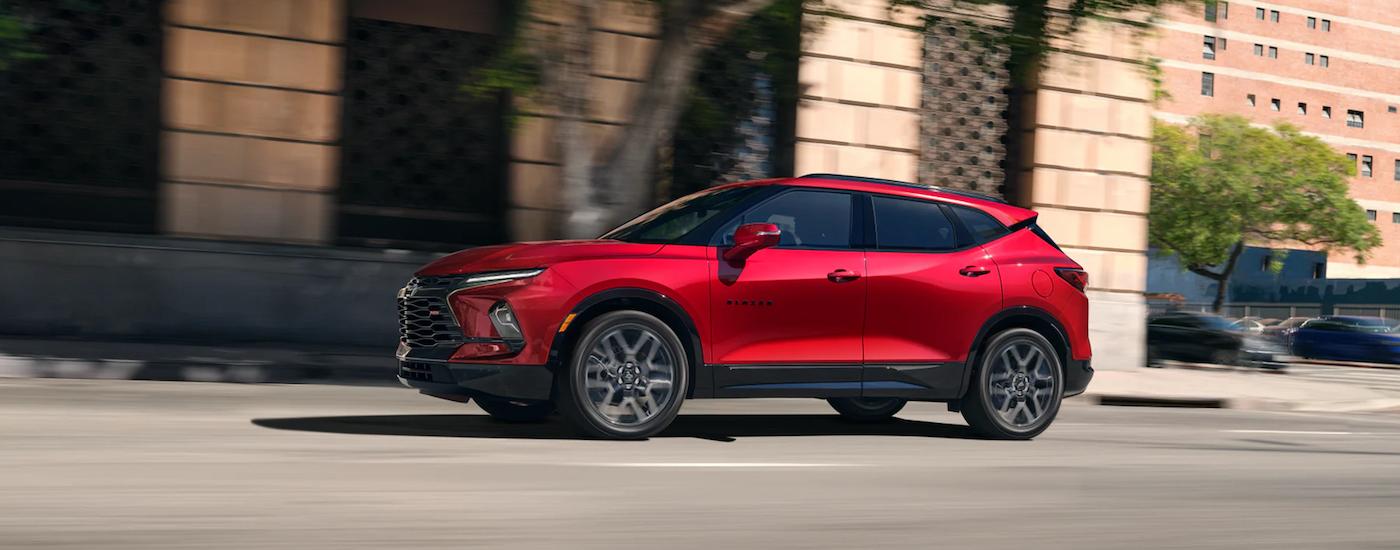 A red 2023 Chevy Blazer RS for sale driving on a city street.