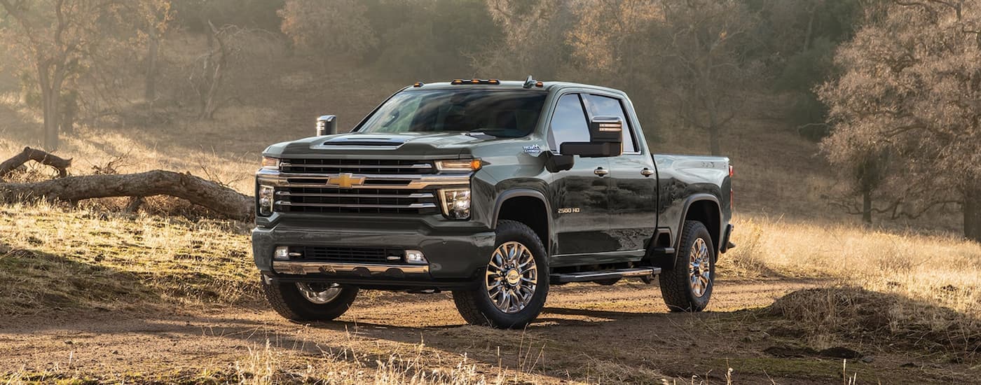 A black 2023 Chevy Silverado 2500HD High Country for sale parked on a dirt path in the woods.