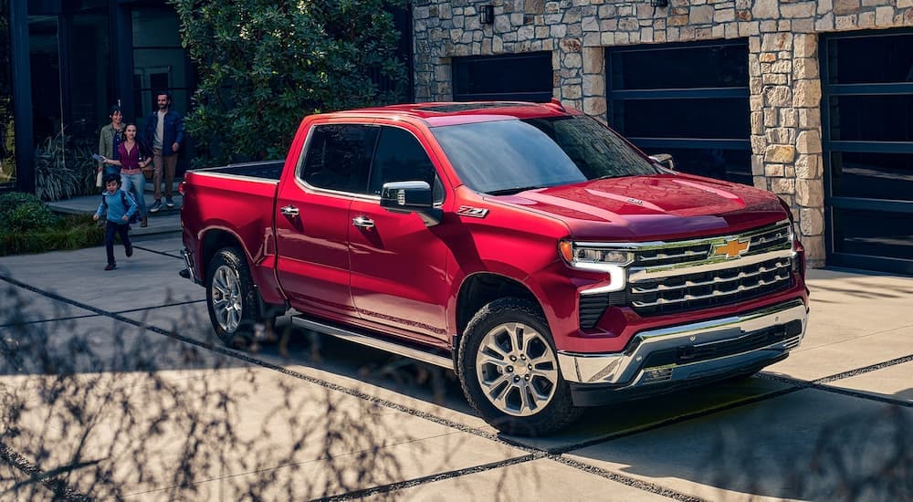 A red 2022 Chevy Silverado 1500 Z71 is shown in a driveway next to a family.