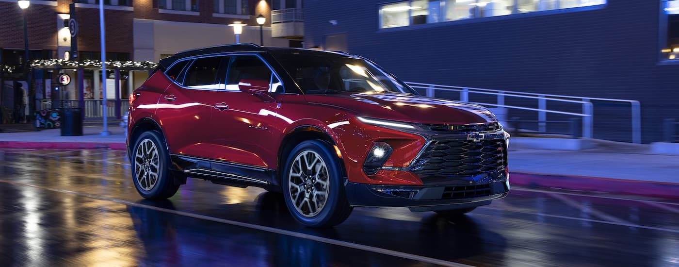A red 2023 Chevy Blazer RS is shown driving on a city street at night.